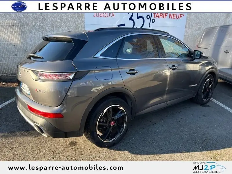DS7 Crossback E-TENSE gris en 3/4 arrière droit, avec jantes noires et feux arrière LED distinctifs visibles.