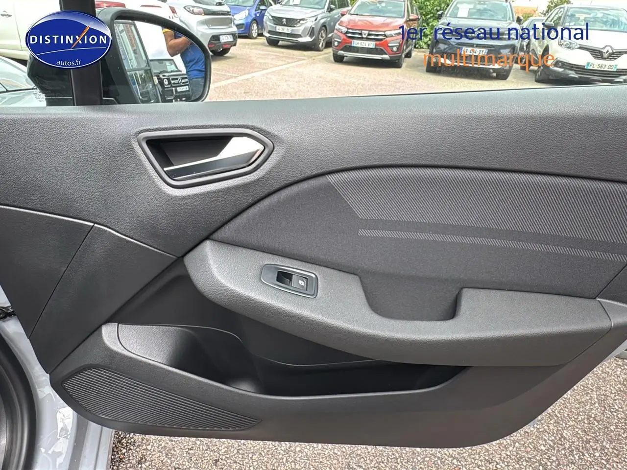 Intérieur montrant la porte côté gauche de la Renault Clio V gris rafale avec poignée argentée et commande de vitre électrique.