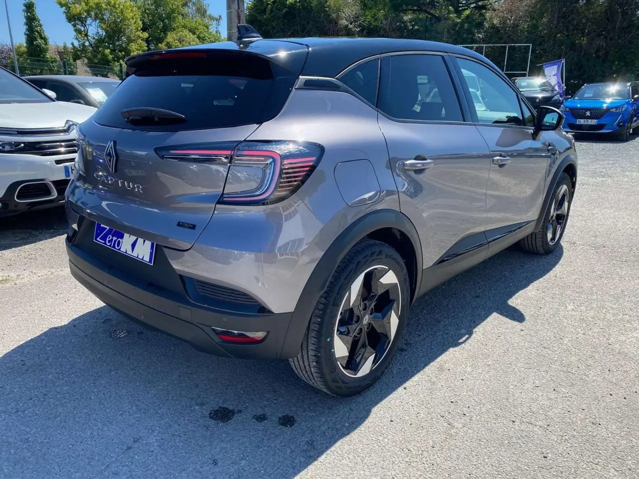 Vue 3/4 arrière droite du Renault Captur 1.6 E-Tech Hybride gris Cassiopée avec toit noir étoilé et jantes distinctives.
