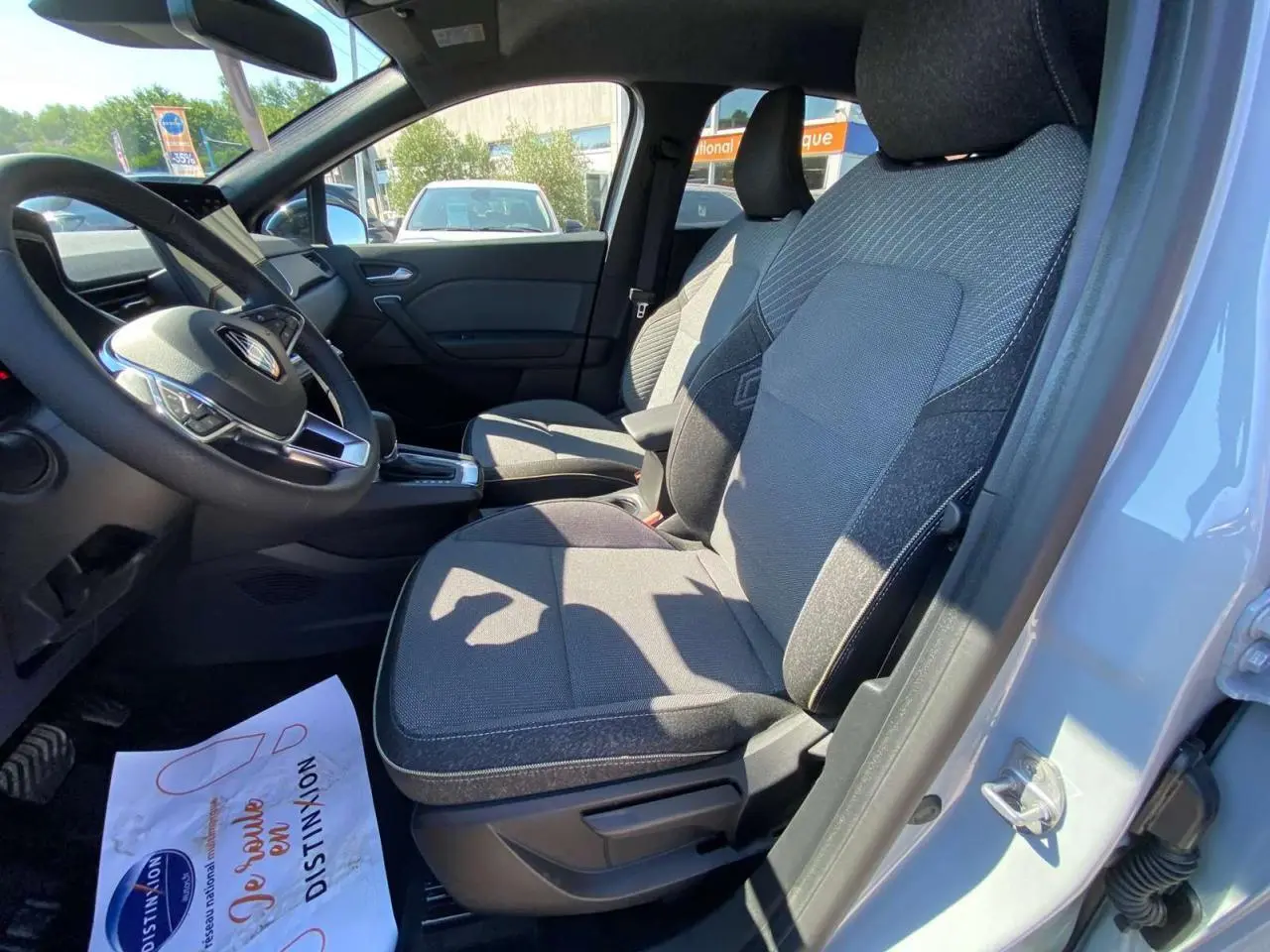 Vue intérieure côté conducteur du Renault Captur 2025 avec sièges tissu gris et volant multifonction noir.