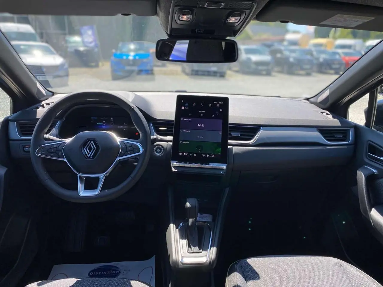 Vue intérieure avant du Renault Captur 2025, tableau de bord moderne avec écran tactile vertical et volant multifonction noir.