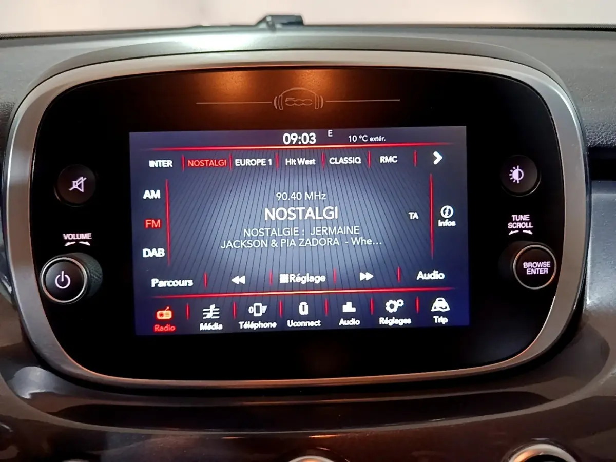 Écran tactile central du tableau de bord de la Fiat 500X gris foncé, affichant la radio sur la station Nostalgie.