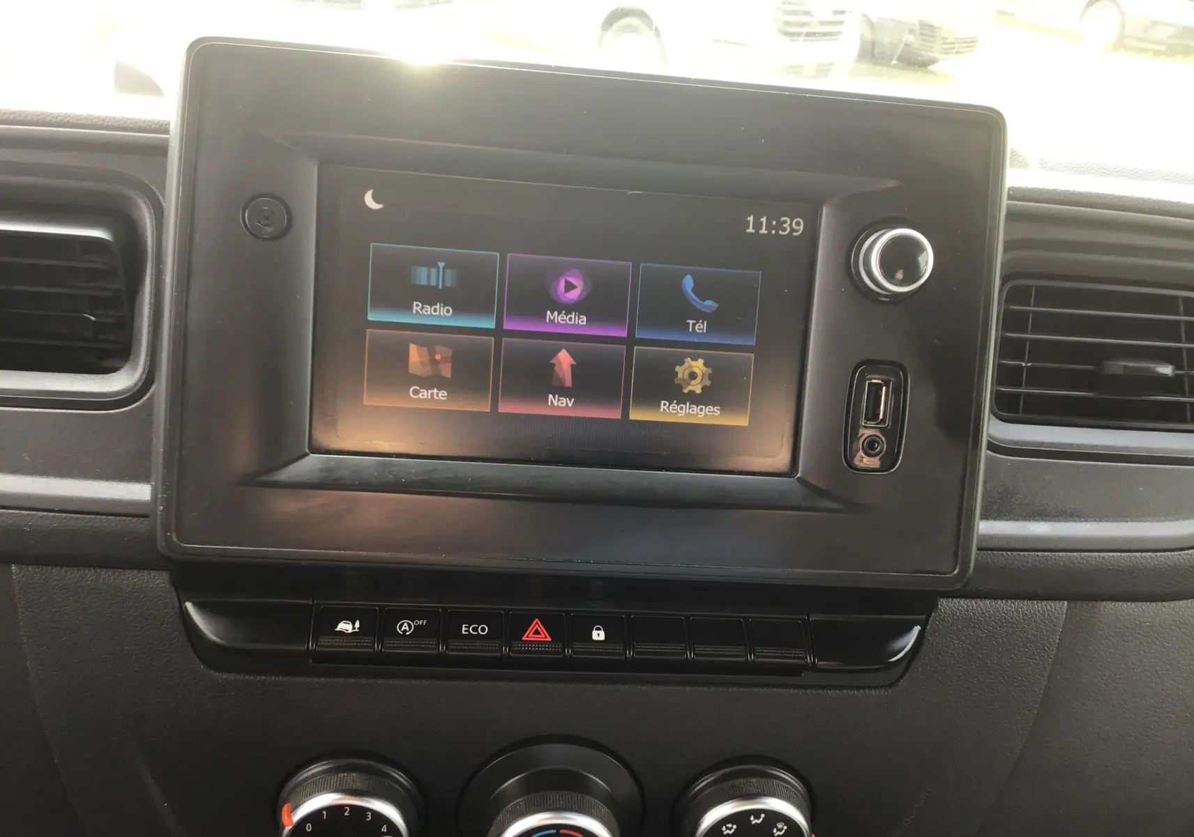 Écran tactile central du tableau de bord du Renault Master blanc, avec commandes climatisation et boutons fonctionnels visibles.