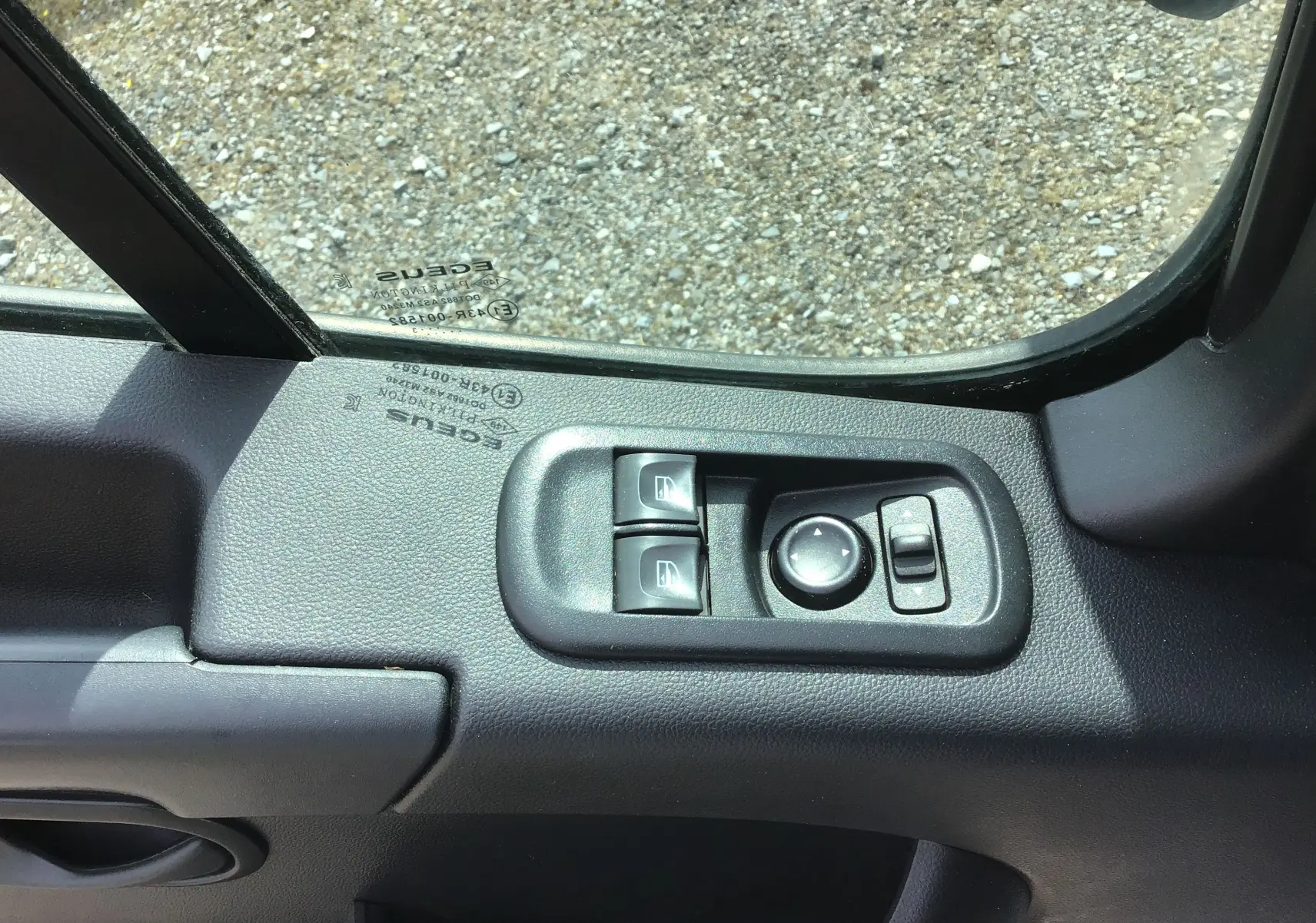 Vue rapprochée des commandes de lève-vitres et réglage des rétroviseurs côté gauche du Renault Master Châssis Cabine blanc 2023.