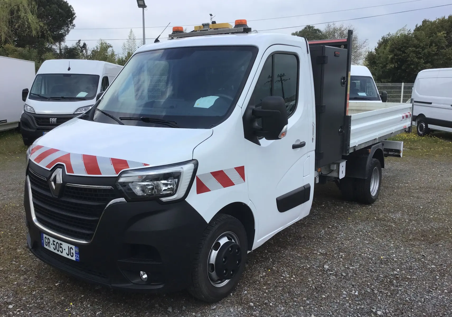 Renault Master Châssis cabine blanc en 3/4 avant droit, avec benne, coffre latéral noir et marquages rouges réfléchissants.