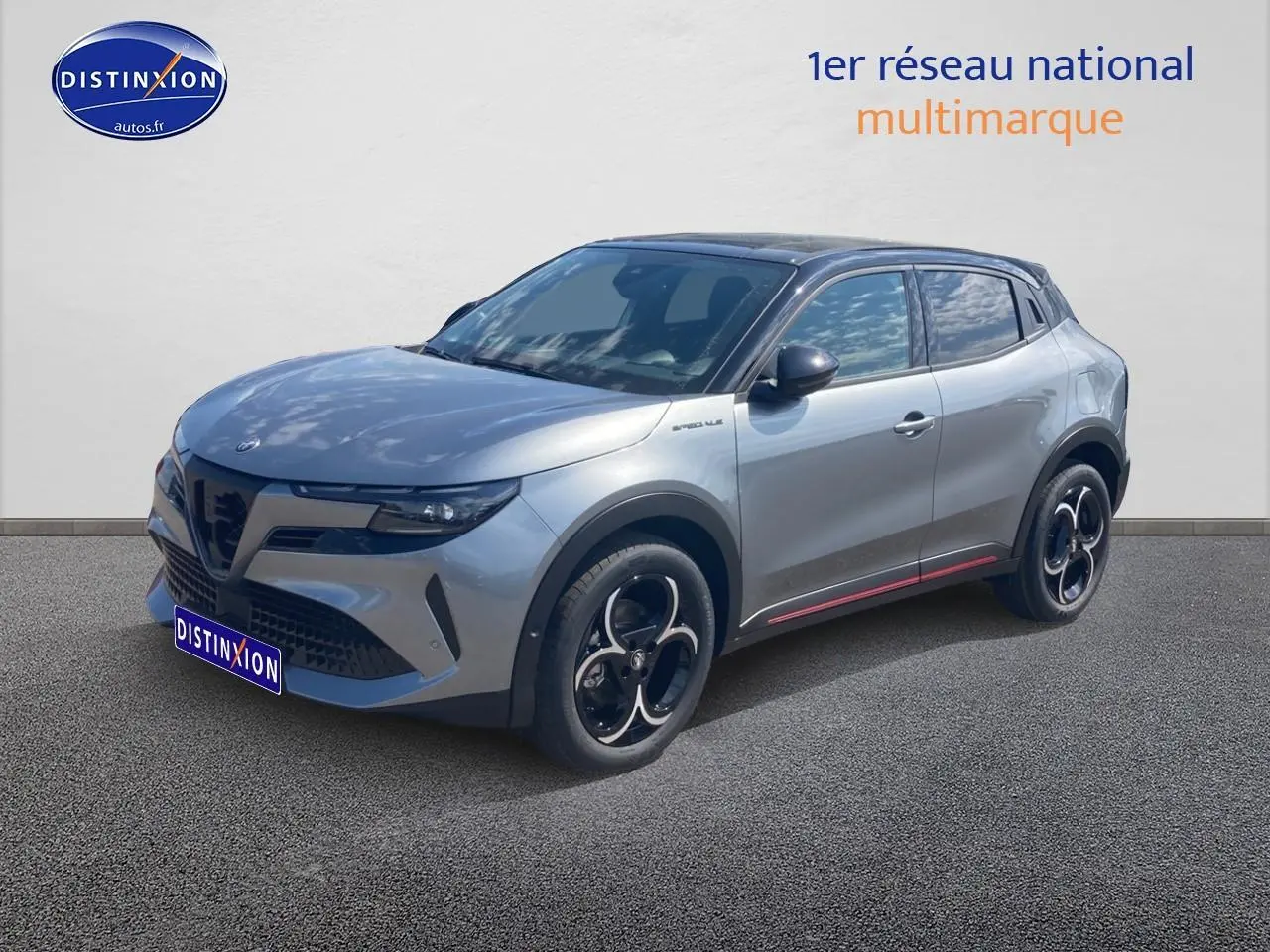 Vue 3/4 avant droite d'une Alfa Romeo Junior gris t/noir avec jantes alliage et vitres teintées.