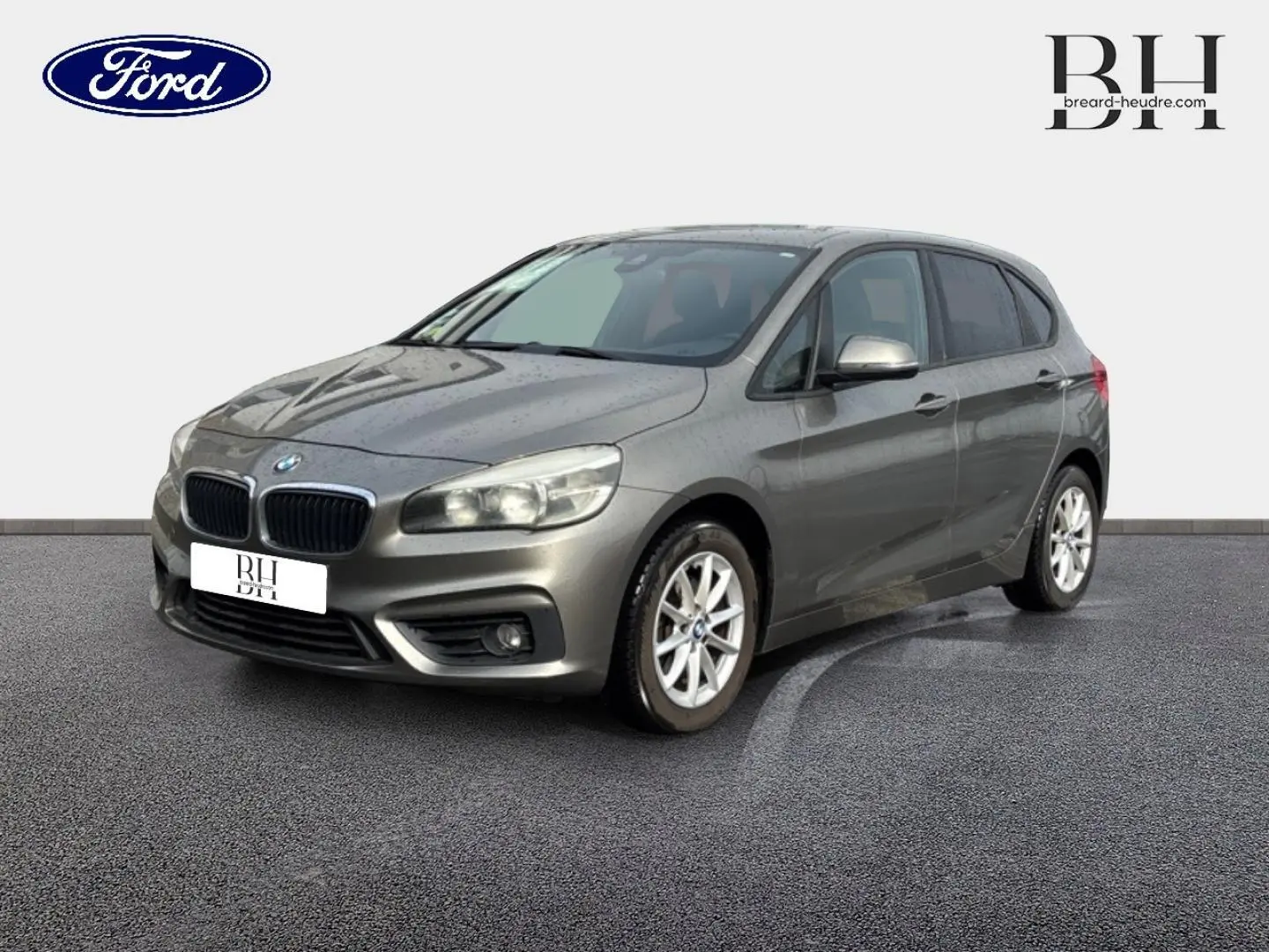 BMW Série 2 Active Tourer 216dA gris platine vue 3/4 avant droit avec jantes alu et feux allumés.