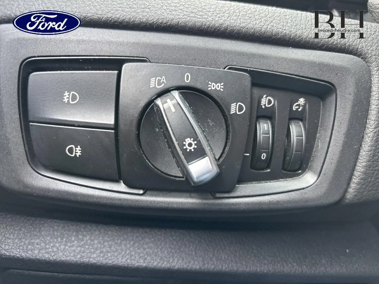 Gros plan sur le panneau de commandes des phares noir dans l’habitacle d’une BMW Série 2 Active Tourer platinumsilber.