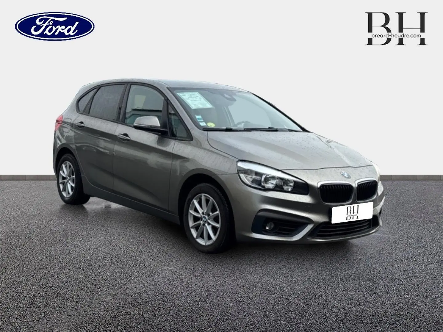 BMW Série 2 Active Tourer 216dA gris platine vue 3/4 avant droit sur sol gris, avec jantes alu et phares LED.