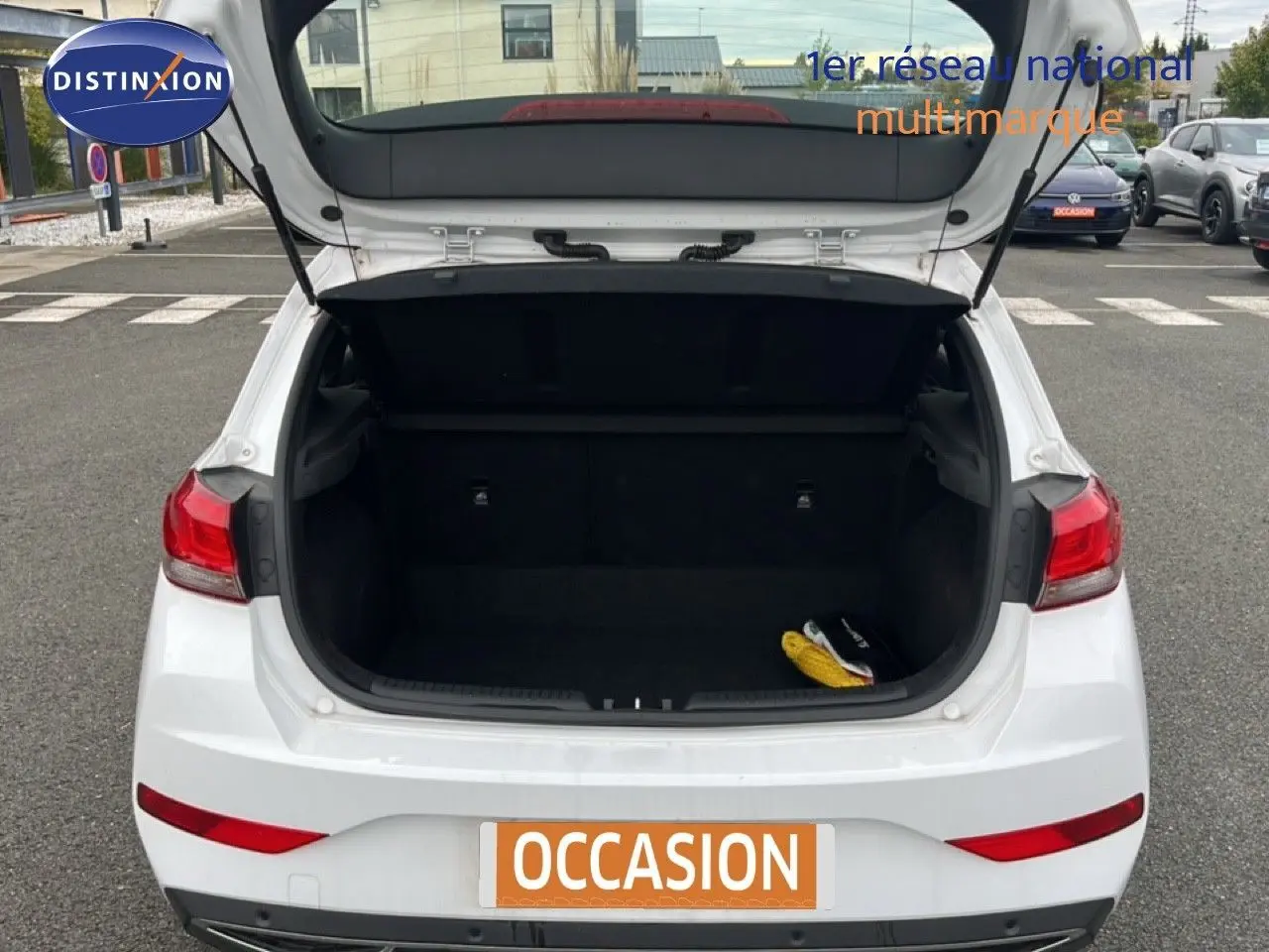 Vue arrière d'une Hyundai i30 blanche nacrée 2023 avec coffre ouvert montrant l'espace de chargement vide.