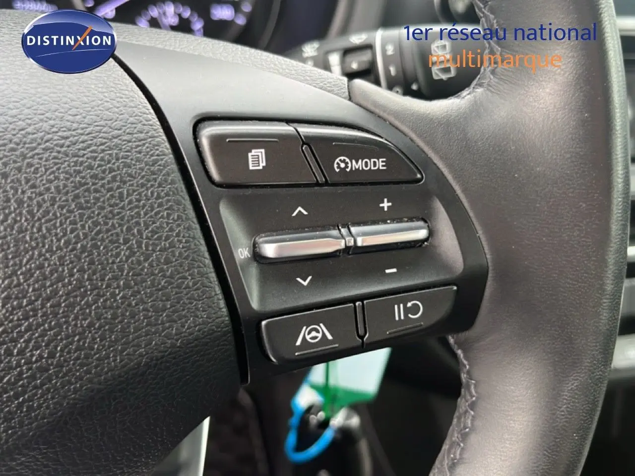 Gros plan sur les commandes au volant d'une Hyundai i30 2023, finition Confort, avec cuir noir et boutons multifonctions.