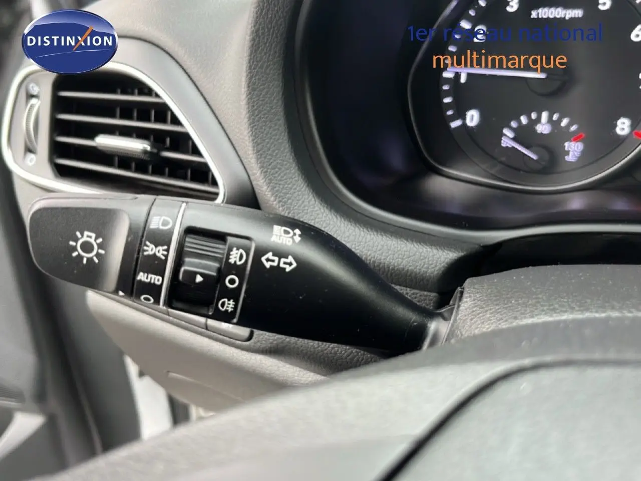 Gros plan sur la commande des phares et clignotants côté gauche du tableau de bord d’une Hyundai i30 blanche nacrée 2023.