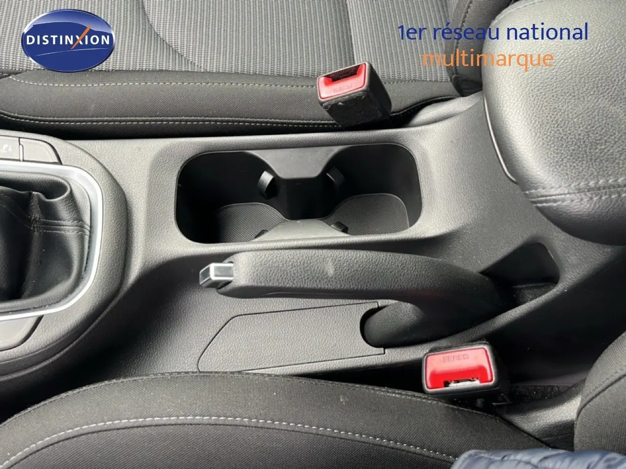 Gros plan intérieur sur la console centrale noire de la Hyundai i30 2023 avec frein à main et porte-gobelets visibles.