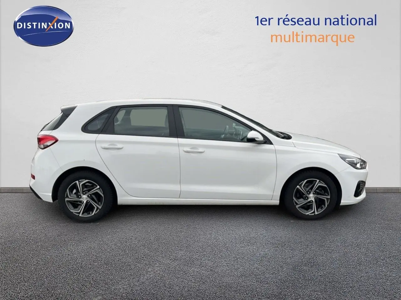 Profil droit d'une Hyundai i30 2023 blanc nacré, compacte 5 portes avec jantes alliage bicolores.