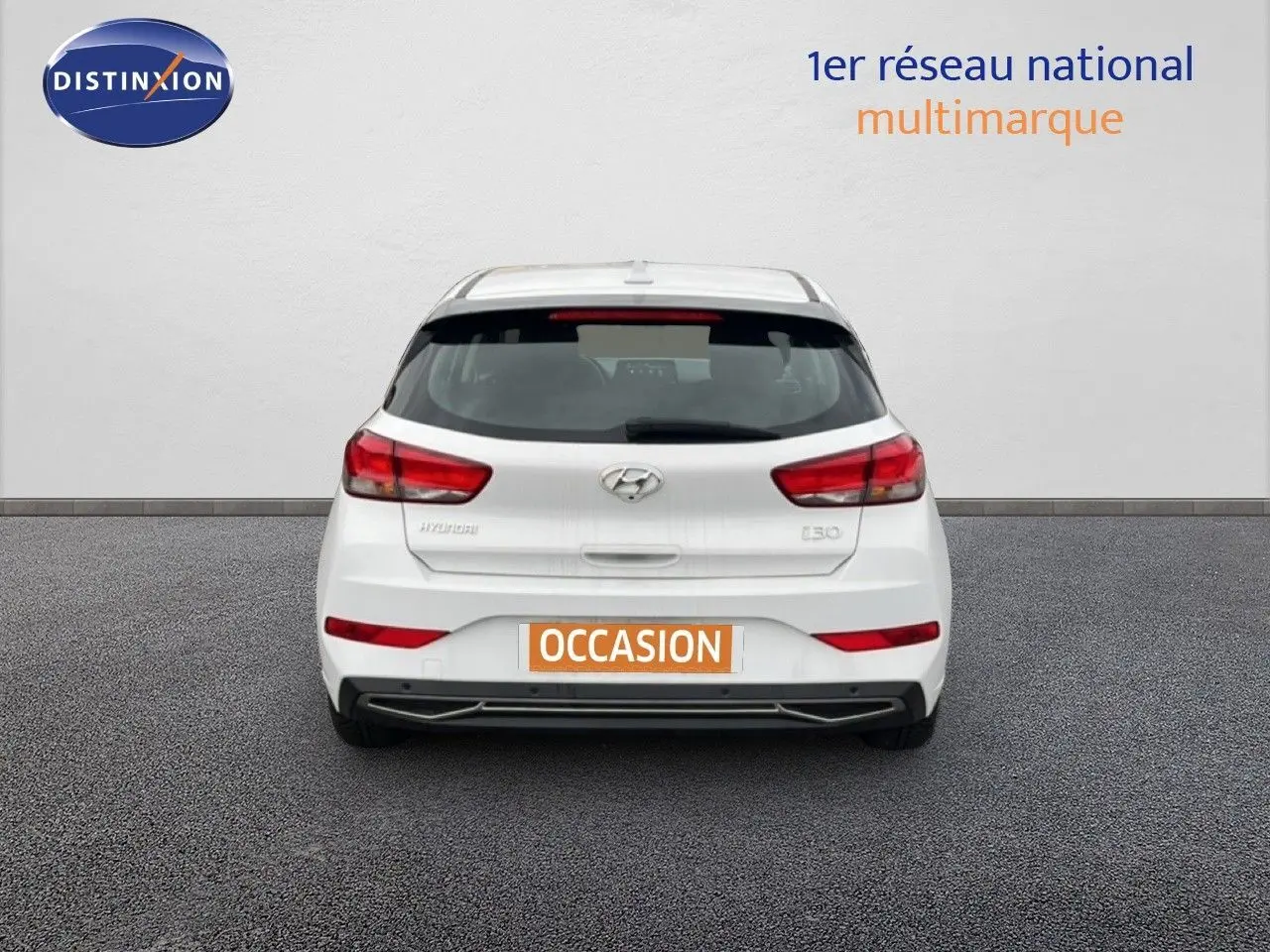 Vue arrière d'une Hyundai i30 blanche nacrée 2023, compacte avec feux arrière rouges et plaque "OCCASION" visible.