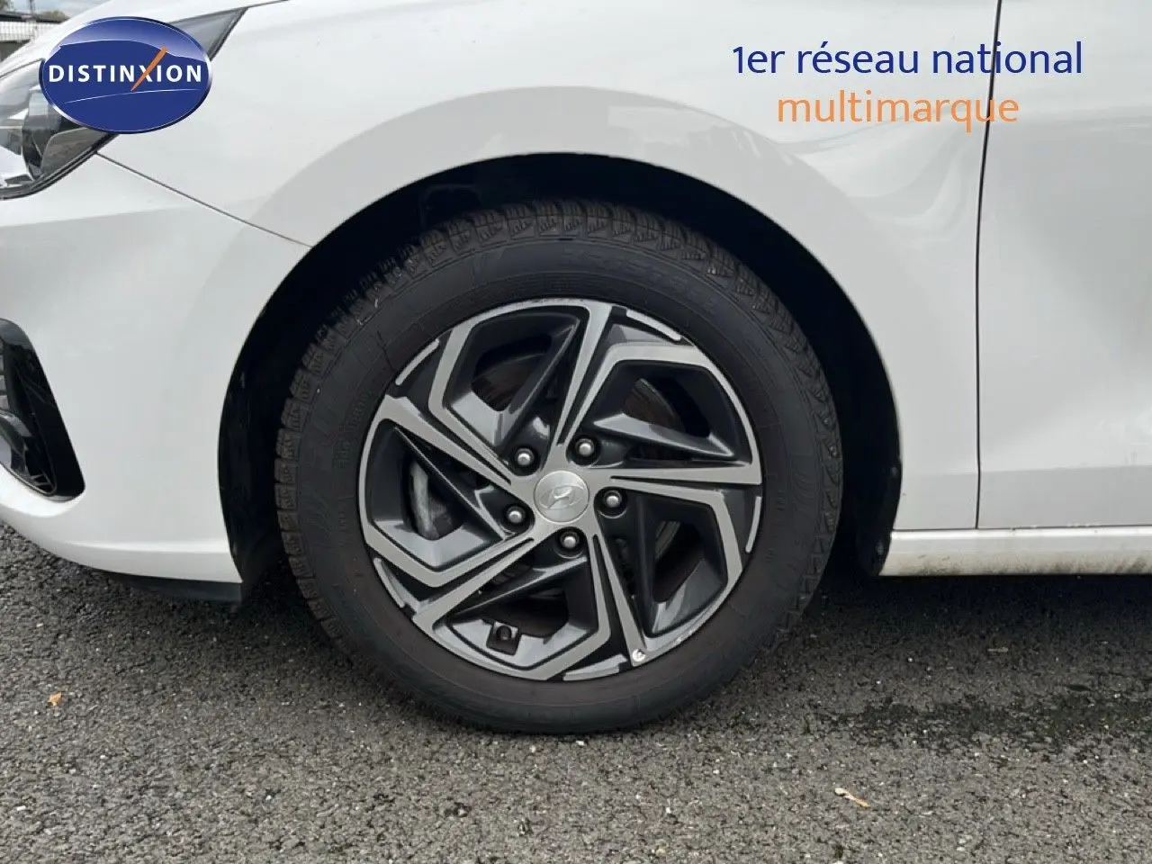 Gros plan sur la roue avant droite d'une Hyundai i30 blanche nacrée avec jante alliage bi-ton 16 pouces.
