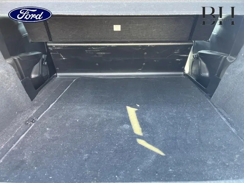 Coffre spacieux vu de face, revêtement noir avec cache-bagages et compartiments latéraux visibles.