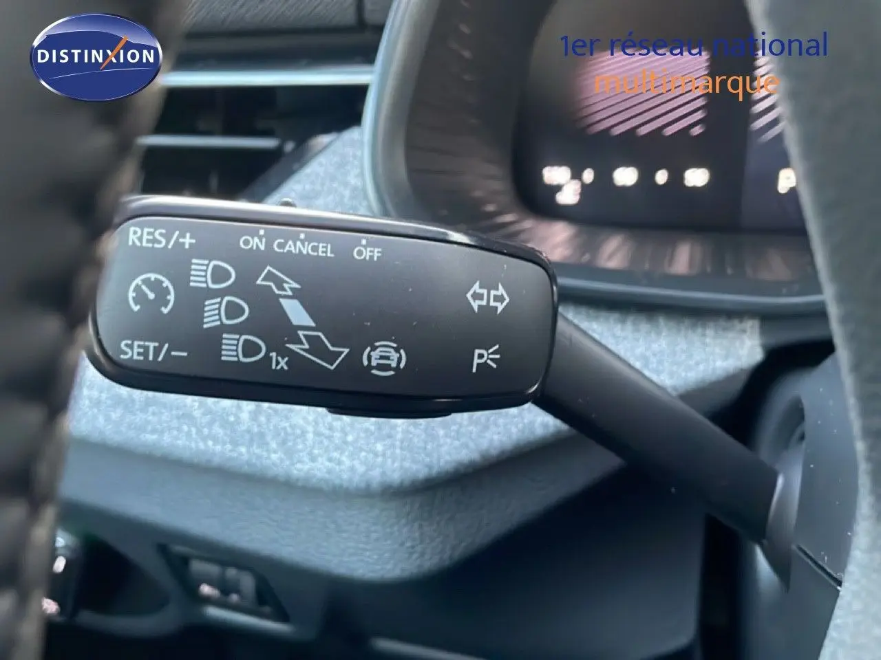 Gros plan sur la commande de régulateur de vitesse à gauche du volant dans l'habitacle gris du Skoda Kamiq.