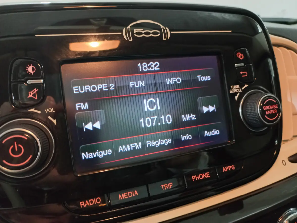 Écran tactile central noir de la Fiat 500 2018 affichant une radio FM avec commandes autour et logo 500 au-dessus.