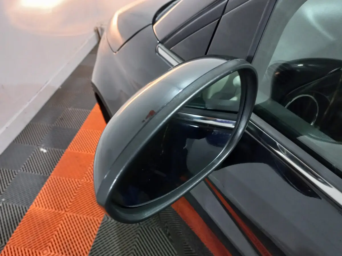 Rétroviseur côté gauche en gros plan sur une FIAT 500 noire, avec reflet de l'habitacle et carrosserie visible.