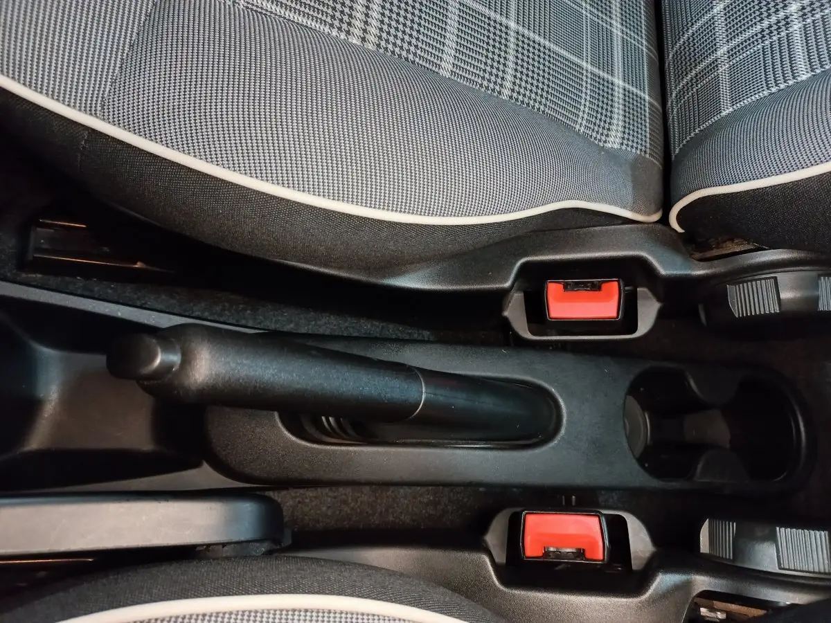 Vue rapprochée de la console centrale avec frein à main manuel et sièges tissu noir à motifs gris de la Fiat 500 Lounge 2018.