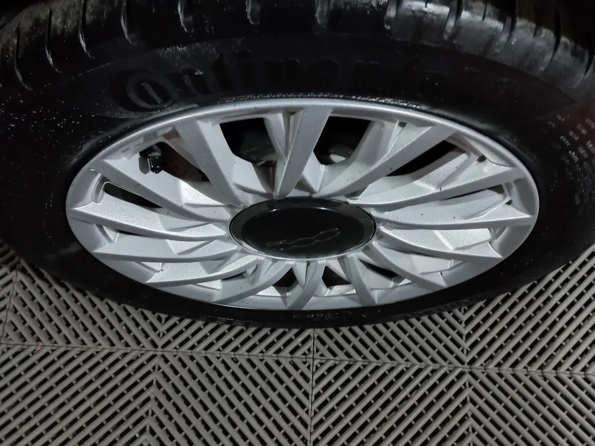 Gros plan sur la jante argentée d'une FIAT 500 noire, mettant en valeur le logo central et le pneu Continental.