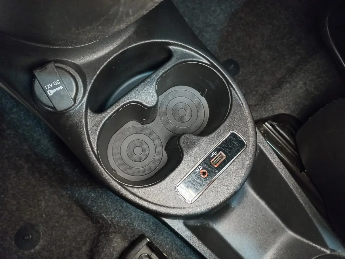 Gros plan sur la console centrale noire de la Fiat 500 Lounge 2018 avec prises USB, AUX et porte-gobelets.