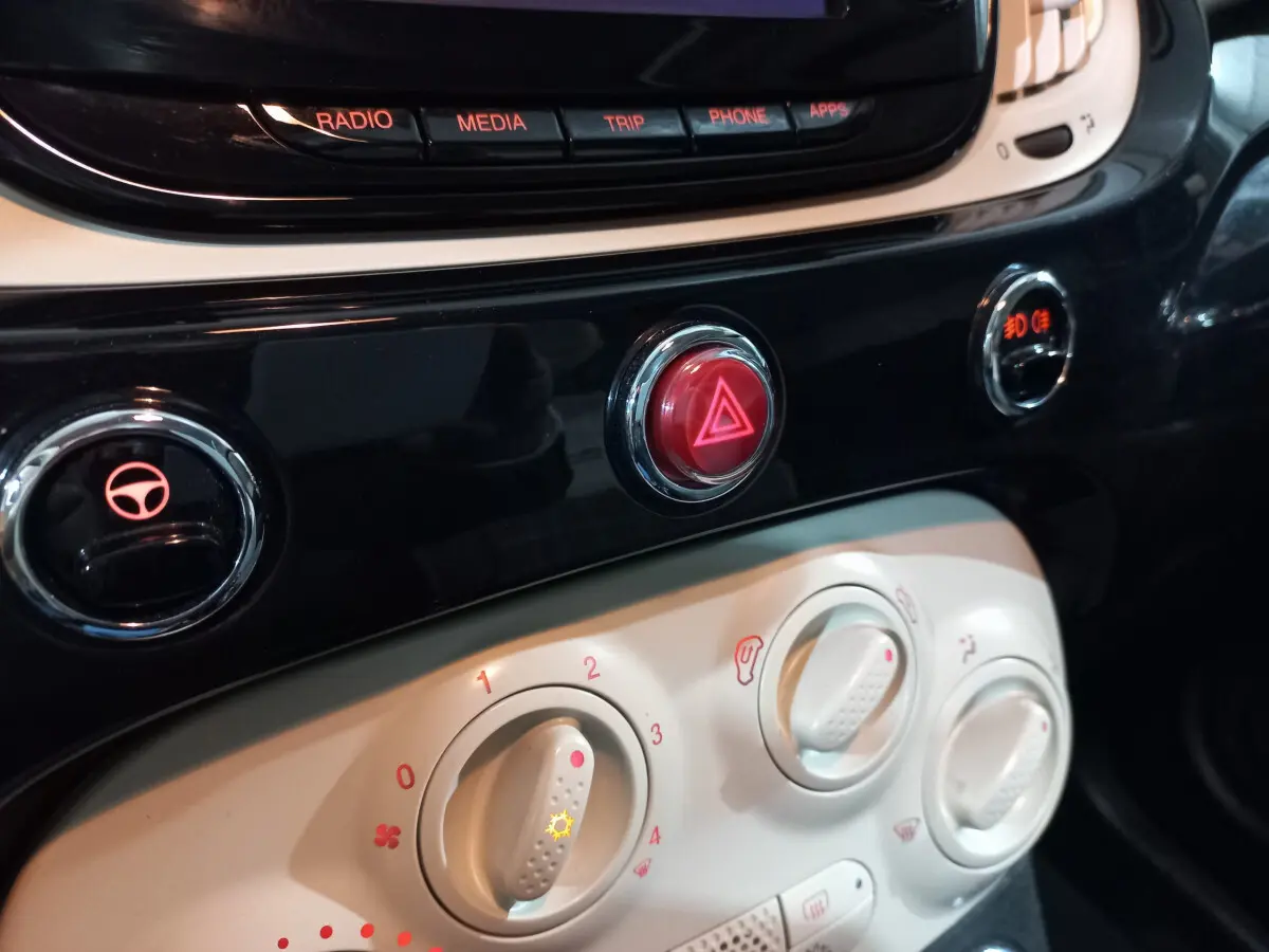 Gros plan sur la console centrale noire et blanche de la Fiat 500 Lounge 2018, avec boutons de climatisation et alerte.
