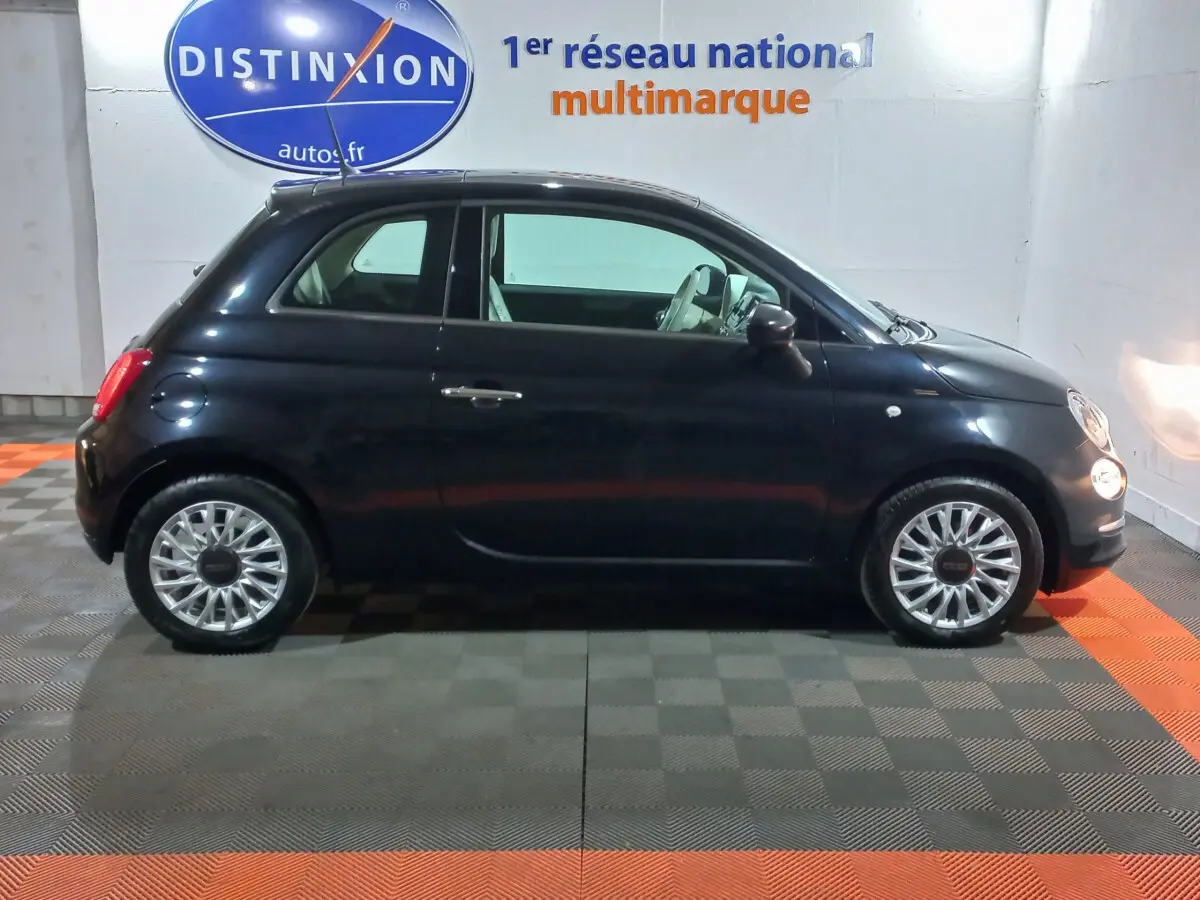 Profil côté droit d'une Fiat 500 noire 2018 avec jantes alliage et intérieur clair visible en showroom.