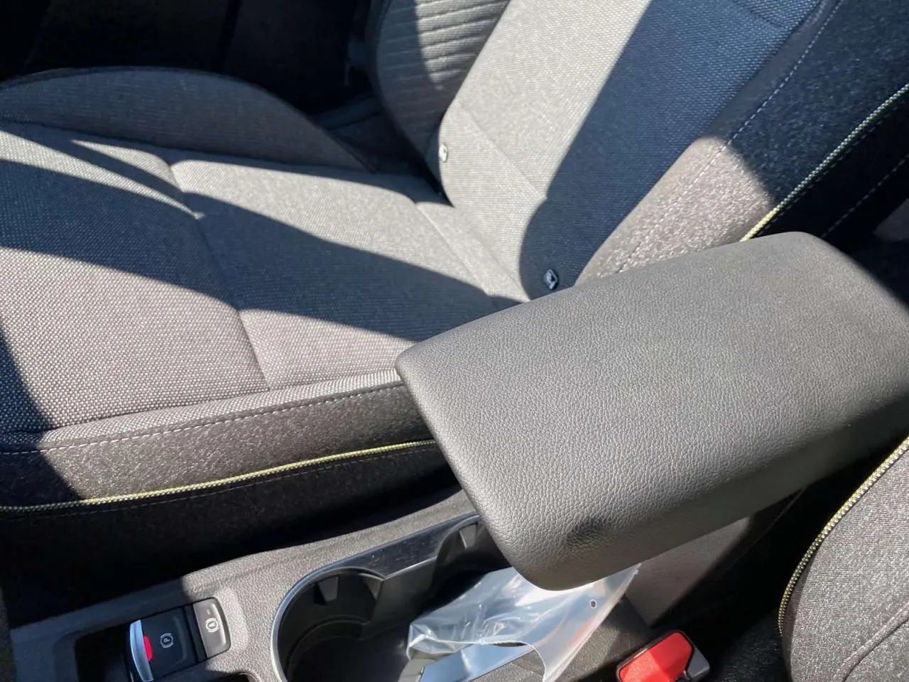 Gros plan sur l'accoudoir central et les sièges gris foncé avec surpiqûres jaunes du Renault Captur 2025.