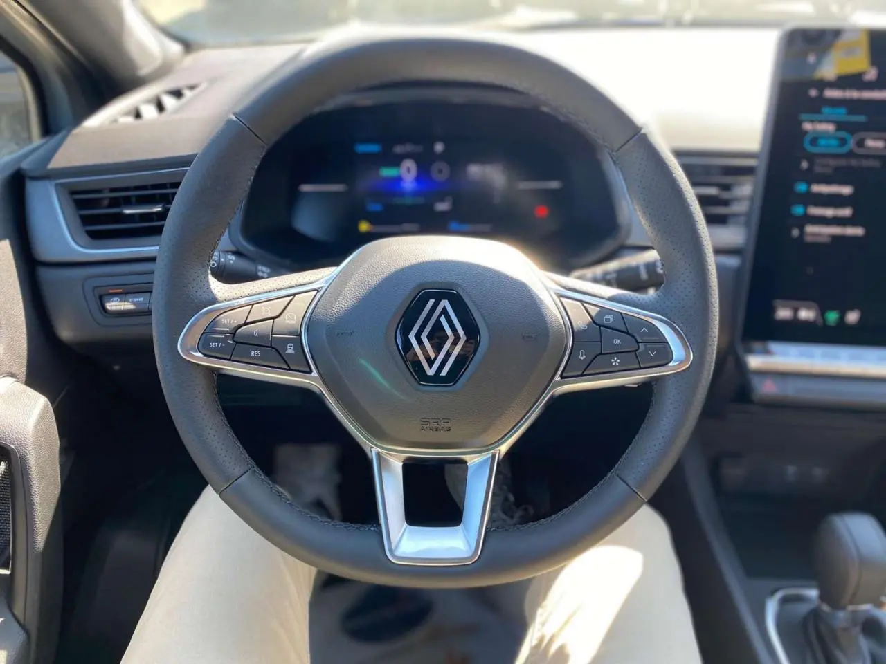 Volant multifonction Renault Captur 2025 en gros plan, avec tableau de bord numérique et écran tactile à droite.