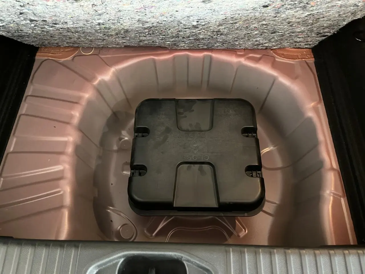 Coffre ouvert montrant le rangement sous plancher rouge métallisé avec boîte à outils noire Renault.