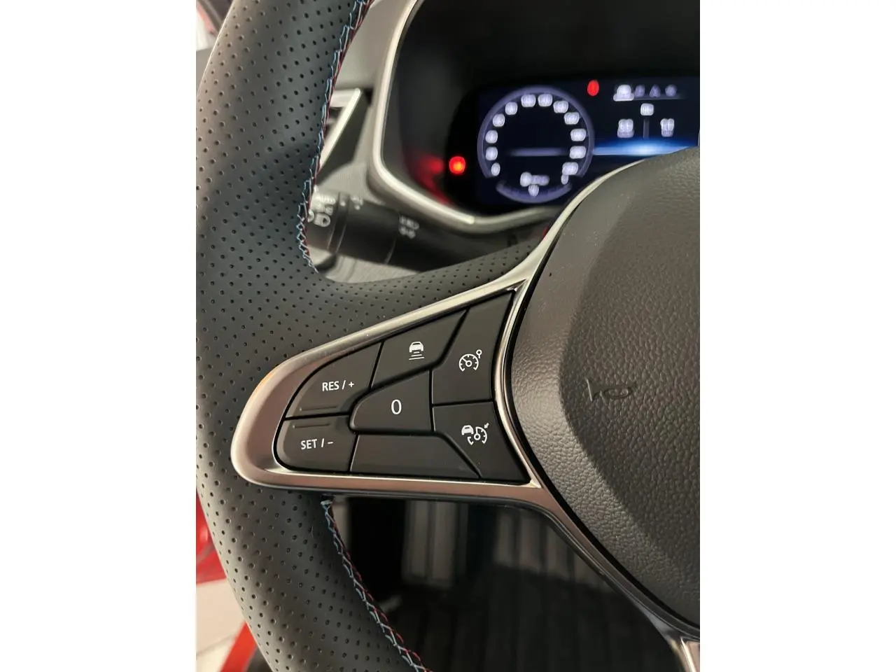 Gros plan sur les commandes à gauche du volant perforé noir avec surpiqûres bleu blanc rouge de la Renault Clio Esprit Alpine rouge 2024