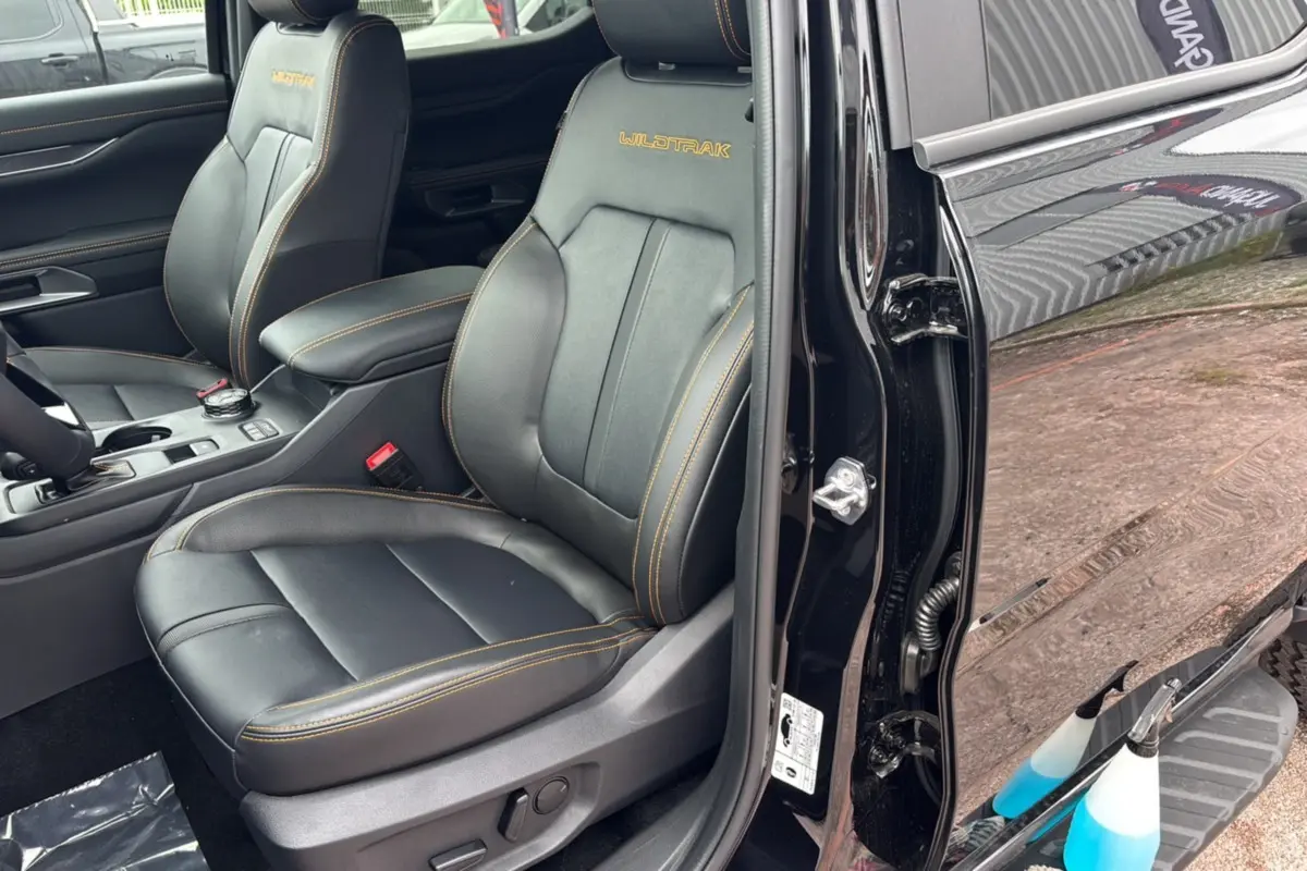 Intérieur du Ford Ranger Wildtrak Plus 2025, siège avant droit en cuir noir agate avec surpiqûres orange visibles.