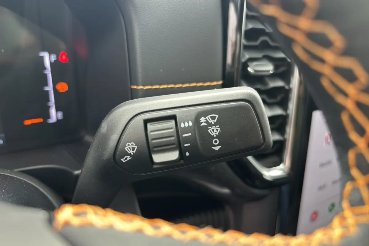 Gros plan sur la commande des essuie-glaces du Ford Ranger 3.0 V6 240 Wildtrak Plus 2025 avec surpiqûres orange visibles.