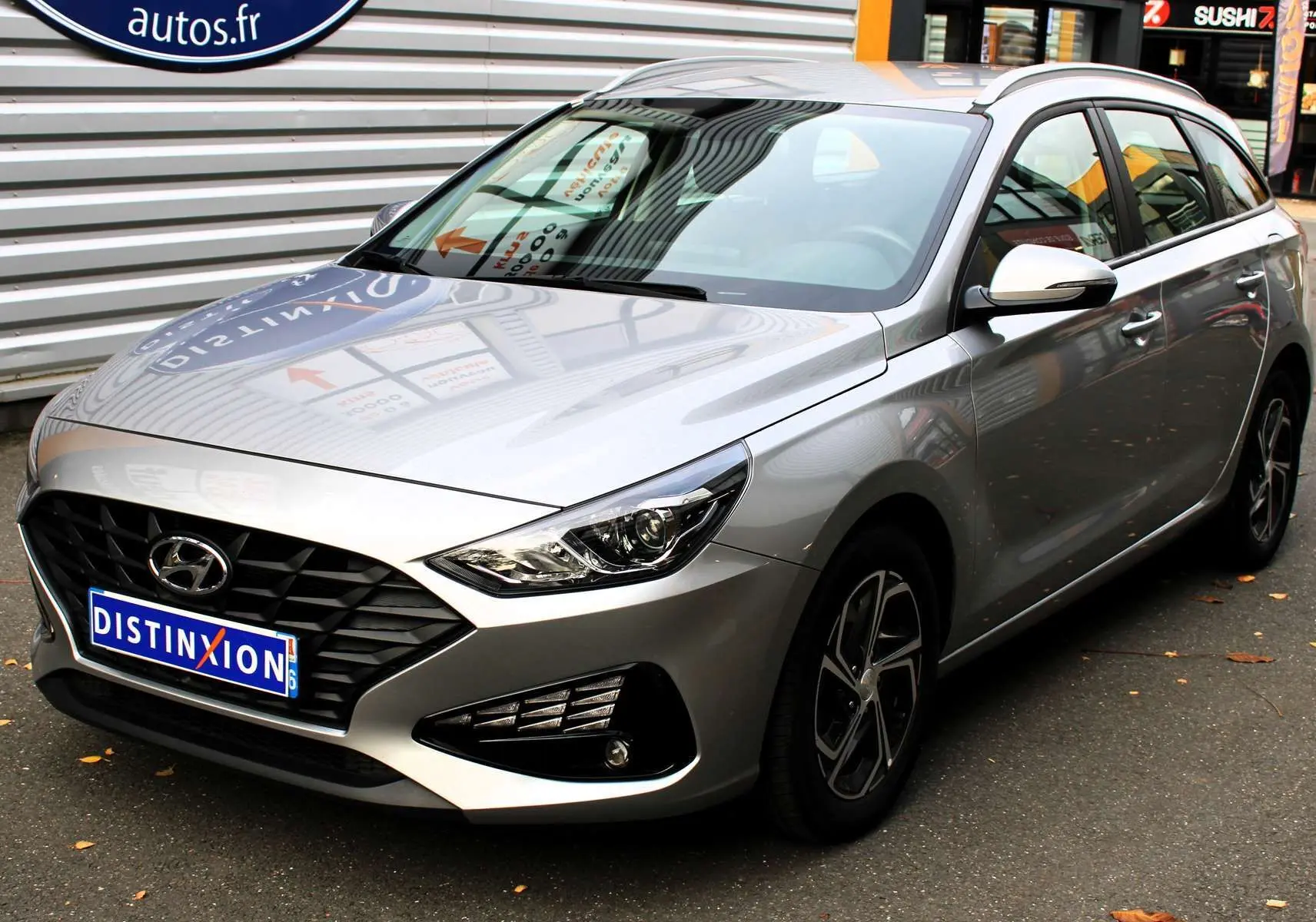 Hyundai i30 SW 2024 argent vue 3/4 avant droit avec calandre noire et jantes alliage bicolores.