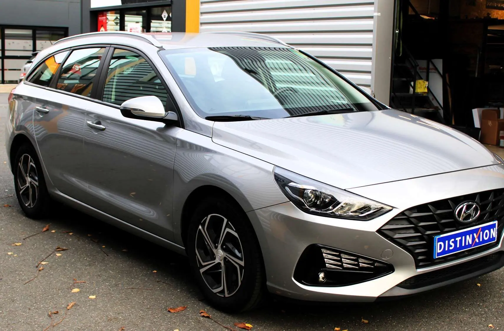Vue 3/4 avant droit d'une Hyundai i30 SW 2024 argent Shimmering Silver avec calandre noire et jantes alliage.
