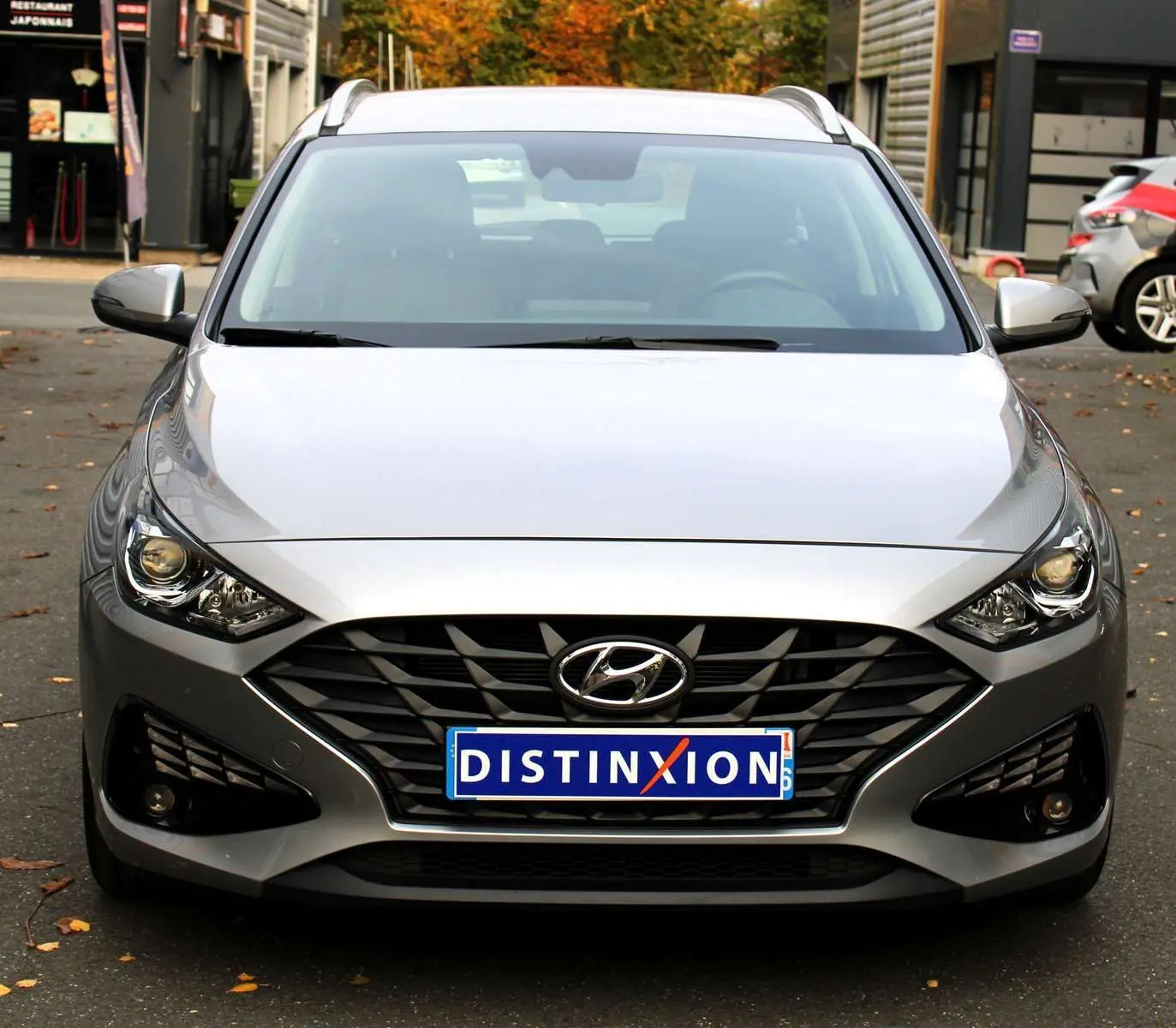 Vue frontale d'une Hyundai i30 SW 2024 en argent scintillant avec calandre noire et phares allumés.