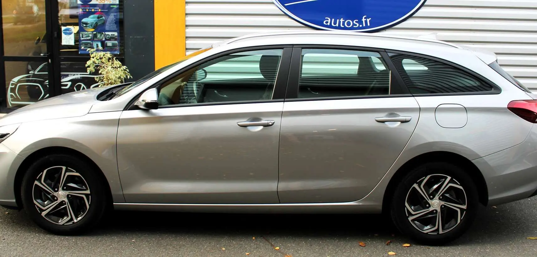 Vue rapprochée du volant noir de la Hyundai i30 SW 2024 avec commandes intégrées et tableau de bord digital.