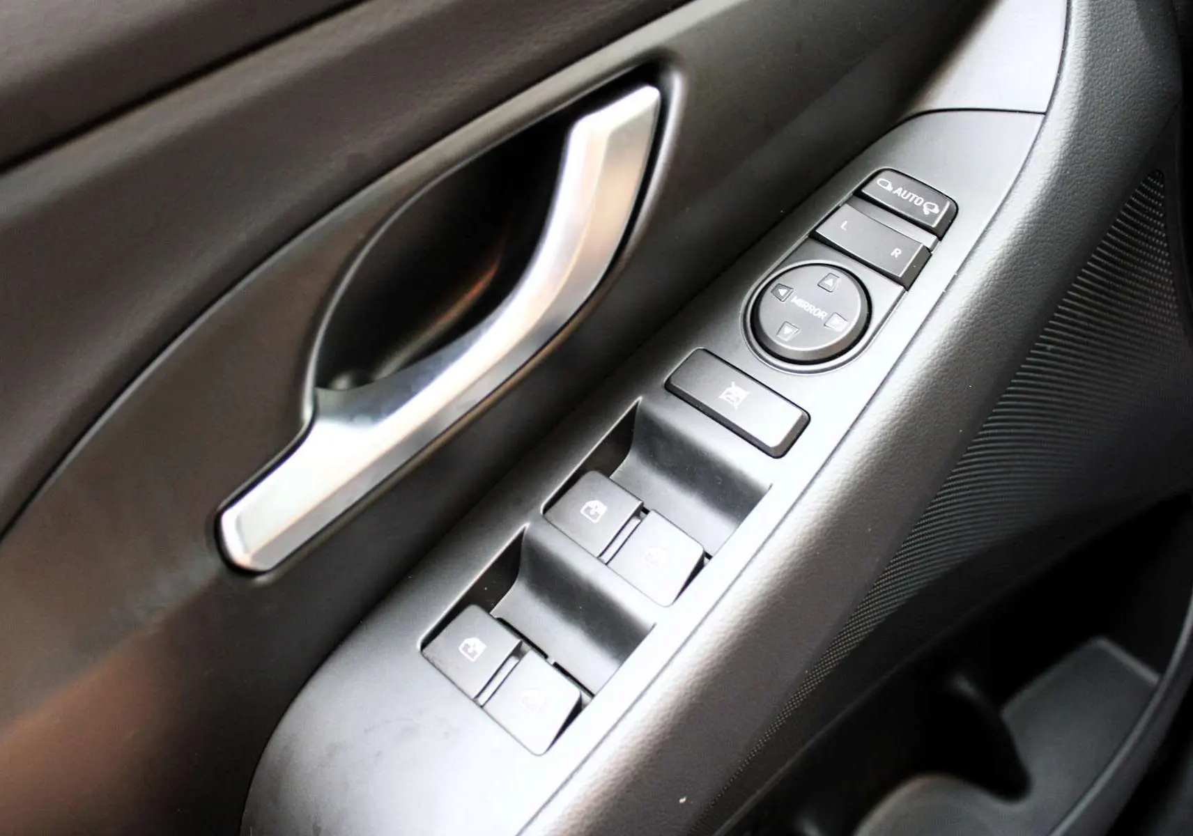 Gros plan sur la commande des vitres et rétroviseurs côté conducteur de la Hyundai i30 SW 2024 finition Creative.