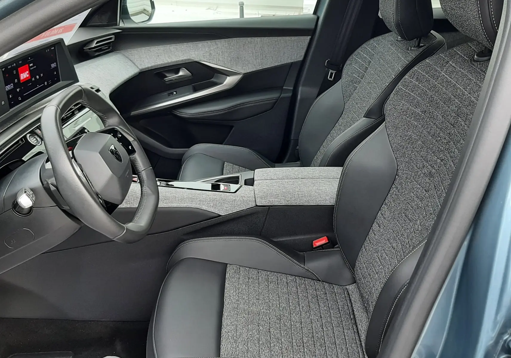 Vue intérieure côté conducteur du Peugeot 3008 III Hybrid 145 Allure avec sièges bi-matière gris et noir, tableau de bord moderne.