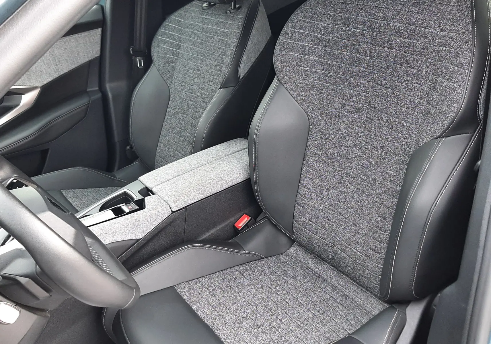 Vue intérieure rapprochée des sièges avant en tissu gris et cuir noir du Peugeot 3008 III HYBRID 145 ALLURE e-DSC6.