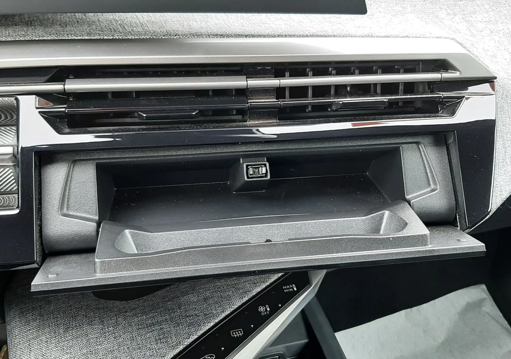 Intérieur du Peugeot 3008 III Hybrid 145 Allure, vue rapprochée de la boîte à gants ouverte et de la console centrale noire.