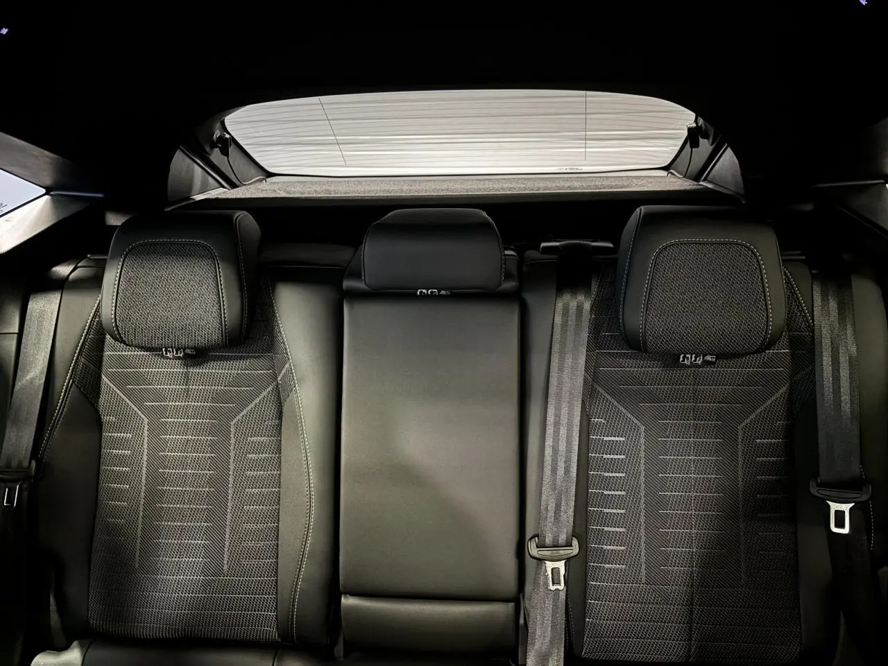 Vue arrière des sièges arrière noirs du Peugeot 3008 Hybrid 2025, avec appuie-têtes et ceintures visibles.