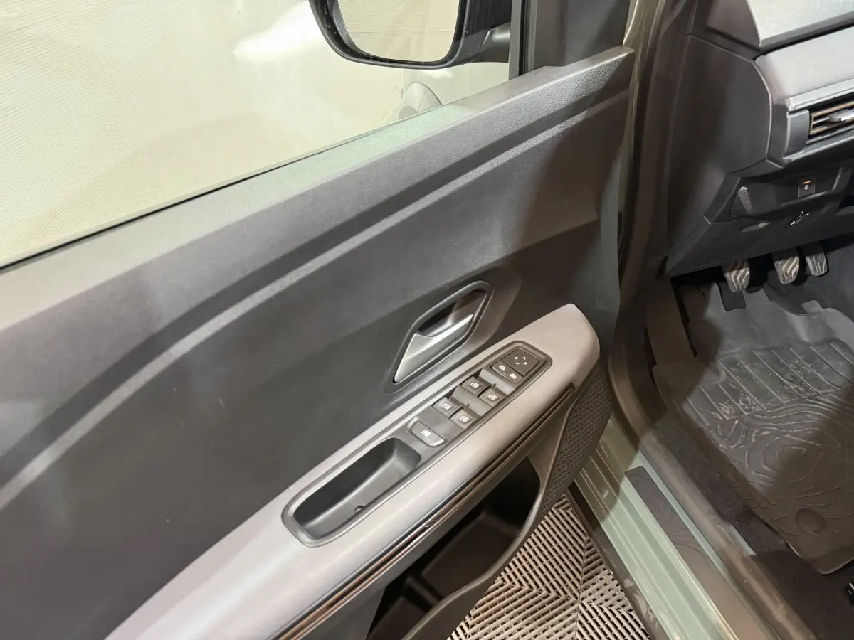 Vue intérieure côté conducteur de la porte verte d'une Dacia Sandero 2024 avec commandes électriques et poignée grise.
