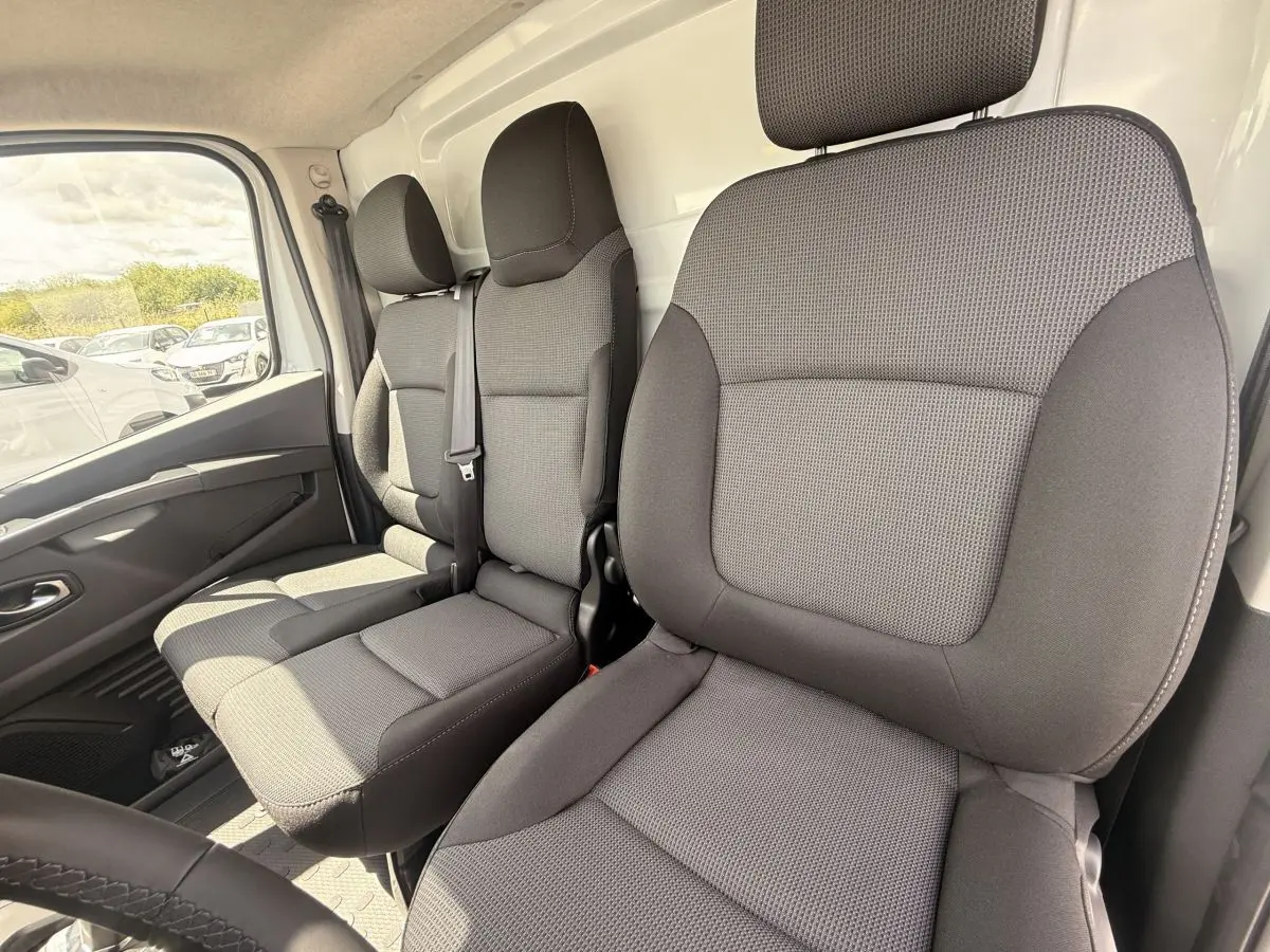 Vue intérieure avant droite sur les sièges gris du Renault Trafic Fourgon blanc, version 2025, avec ceinture de sécurité visible.