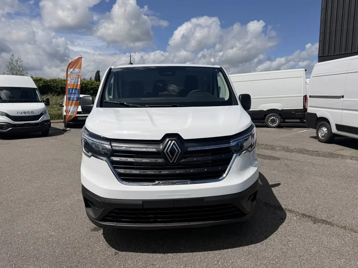 Renault Trafic Fourgon blanc vu de face, avec calandre noire et logo Renault bien visible.