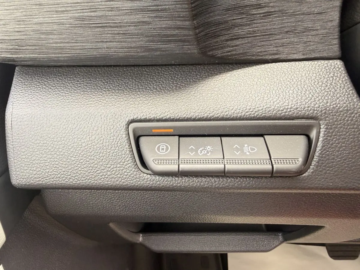 Gros plan sur les commandes de réglage des phares et du tableau de bord du Renault Trafic Fourgon blanc.