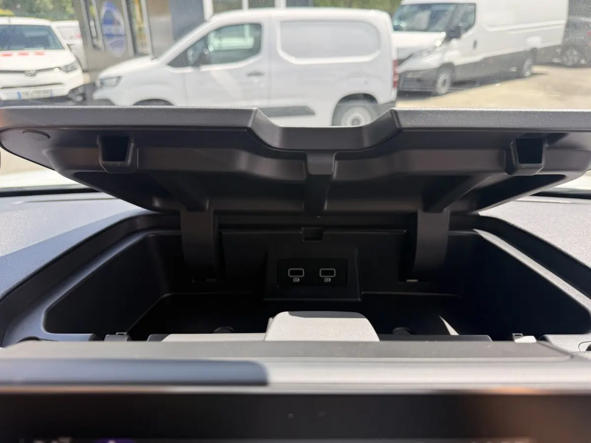 Vue rapprochée du compartiment de rangement ouvert sur le tableau de bord du Renault Trafic Fourgon blanc.