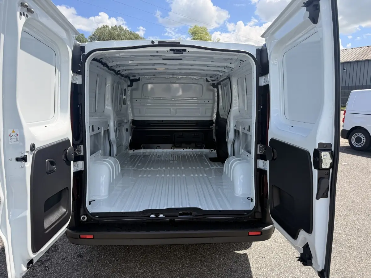 Vue arrière du Renault Trafic Fourgon blanc 2025 avec portes ouvertes montrant l'espace de chargement vide et la cloison pleine.